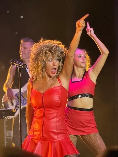Julie and a dancer raising their arms during a performance