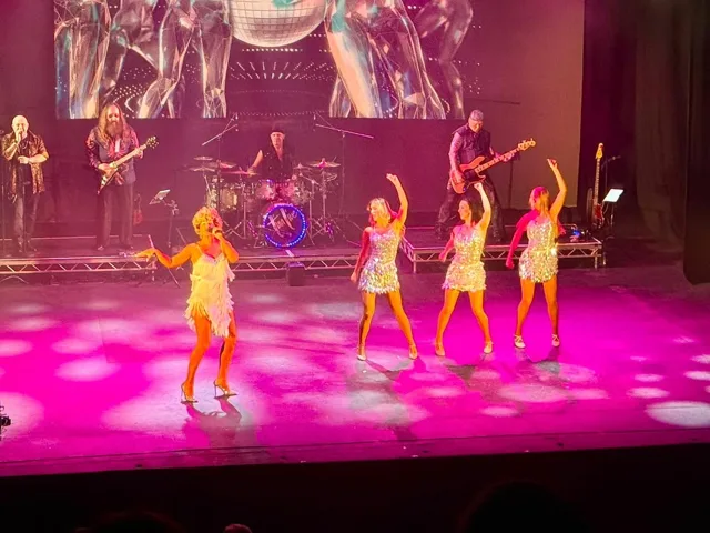 Wide view of Julie, the dancers and the band on stage
